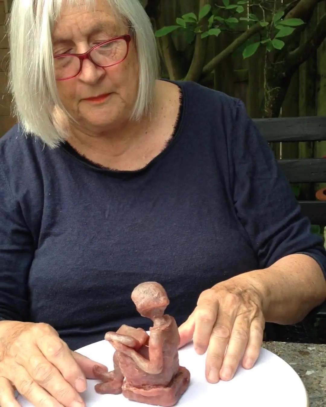 Wilma van der Lee boetseert een zittende figuur in klei